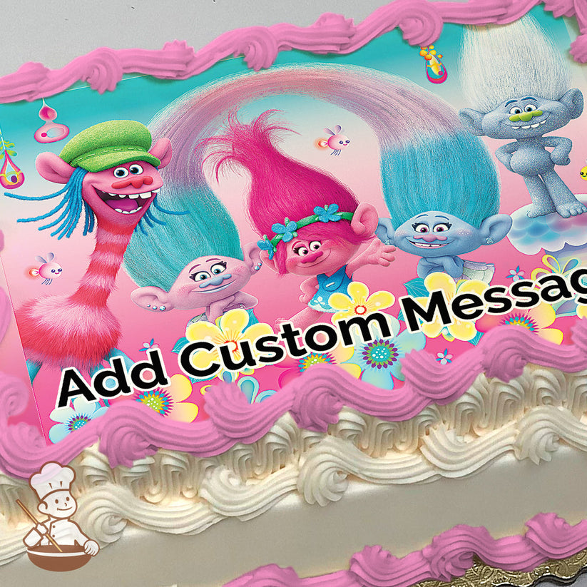 Colorful cartoon trolls with vibrant hair, including a pink-haired troll in the center, surrounded by flowers and a pink-to-blue gradient background, printed on a photo sheet cake.