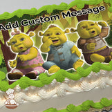 Three cartoon ogre babies are sitting together in a forest with trees and sunlight in the background, printed on a sheet cake.