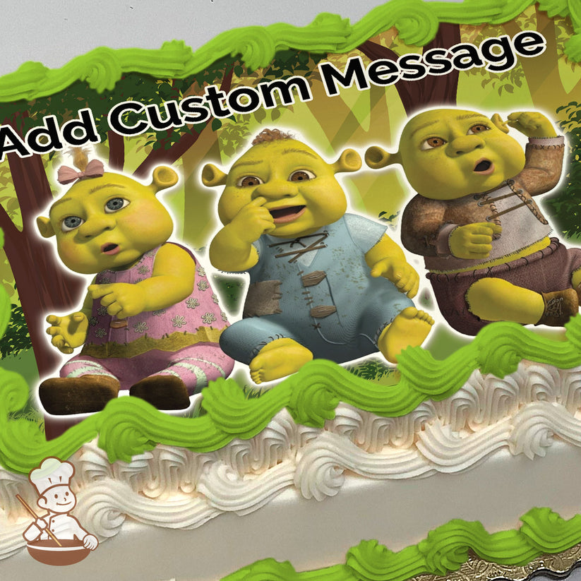 Three cartoon ogre babies are sitting together in a forest with trees and sunlight in the background, printed on a sheet cake.