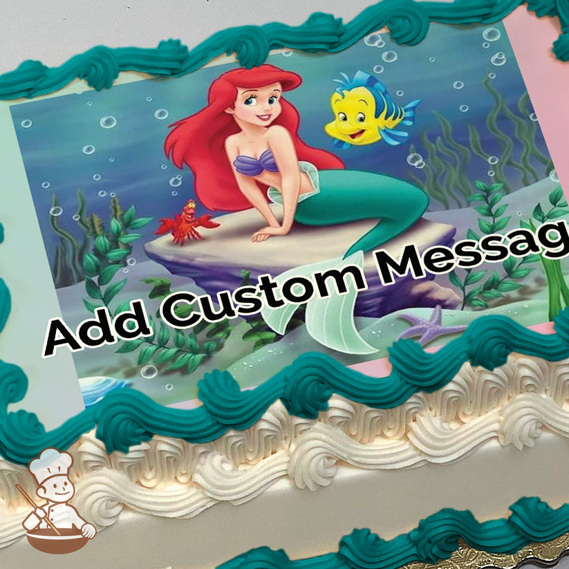 A cartoon image of Ariel, the Little Mermaid, sitting on a rock underwater with Flounder and Sebastian nearby. The background shows sea plants and bubbles. Printed on a sheet cake.