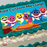 Cartoon sharks and a pink fish character with a snorkel smile underwater near coral and rocks. The background is a bright blue ocean. Printed on a sheet cake.
