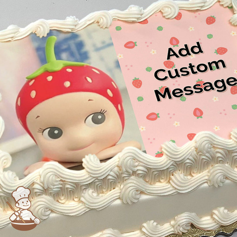 A cartoon character with a strawberry-themed hat smiles with a light blue tiled background. The right side has a pink strawberry pattern. Printed on a sheet cake.