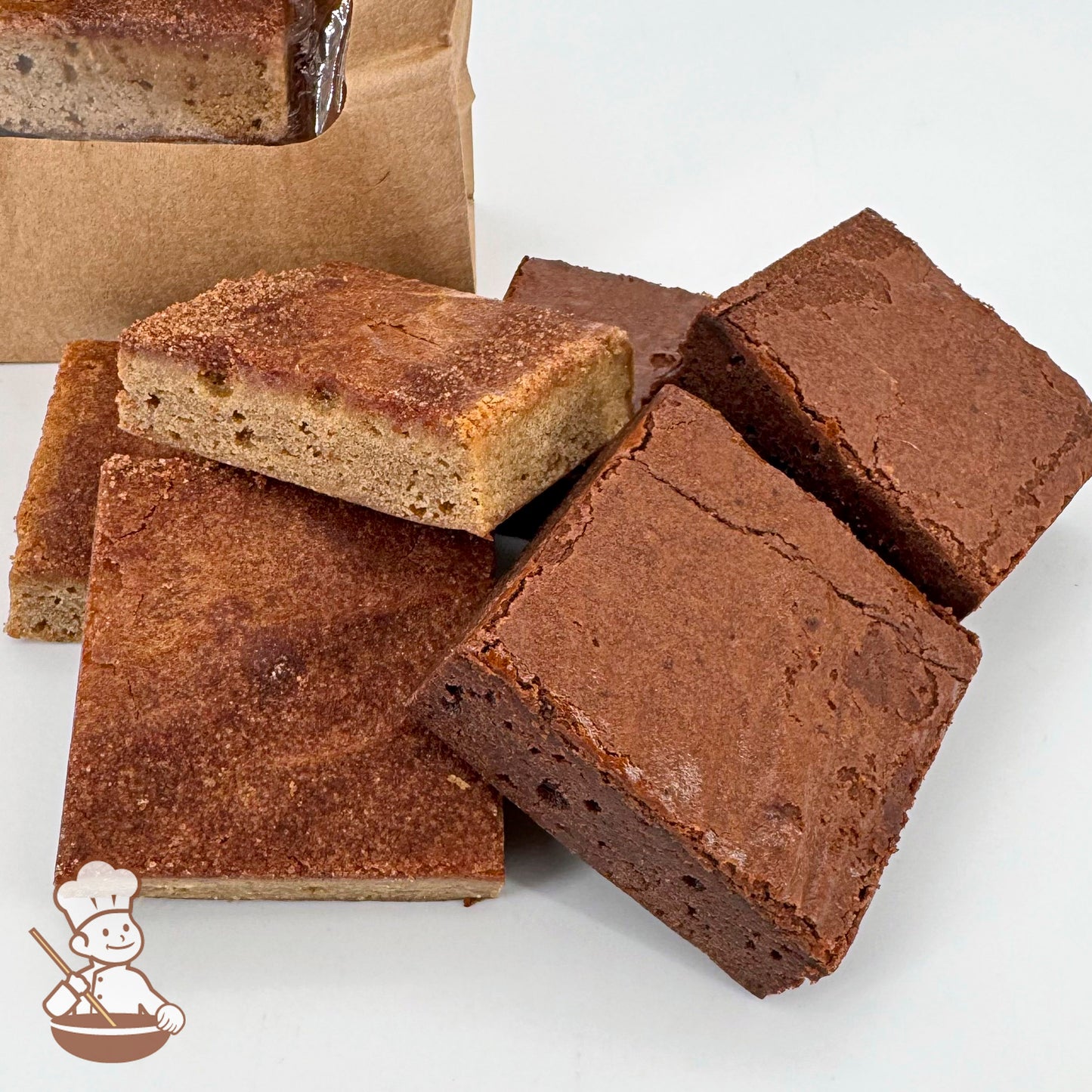 A stack of brownies and snickerdoodle blondies on a white surface, with a brown paper bag in the background.