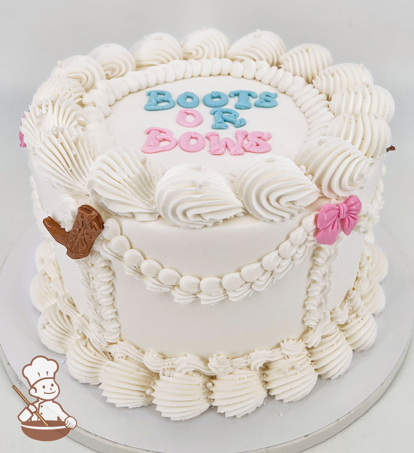 White single-tier cake with piped swirls, pearl accents, and text reading "Boots or Bows" in blue and pink. Decorated with a brown boot and pink bow.