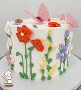 A single-tier white cake decorated with colorful buttercream flowers, including red, yellow, purple, and white blooms, and green stems. Pink butterflies adorn the top.