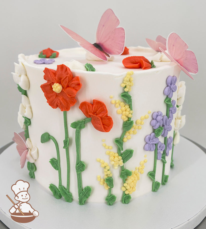 A single-tier white cake decorated with colorful buttercream flowers, including red, yellow, purple, and white blooms, and green stems. Pink butterflies adorn the top.