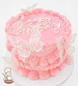 A single-tier pink cake with piped frosting borders, "happy birthday" written on top, and decorated with delicate white butterfly toppers.