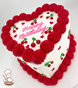 Heart-shaped cake with white frosting, decorated with red piped borders, small red hearts, cherries with green stems, and "Happy Birthday" written in pink icing.