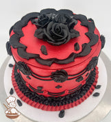 A single-tier cake with vibrant red frosting, decorated with black piped roses, scalloped edges, and intricate black and red accents on a white base.
