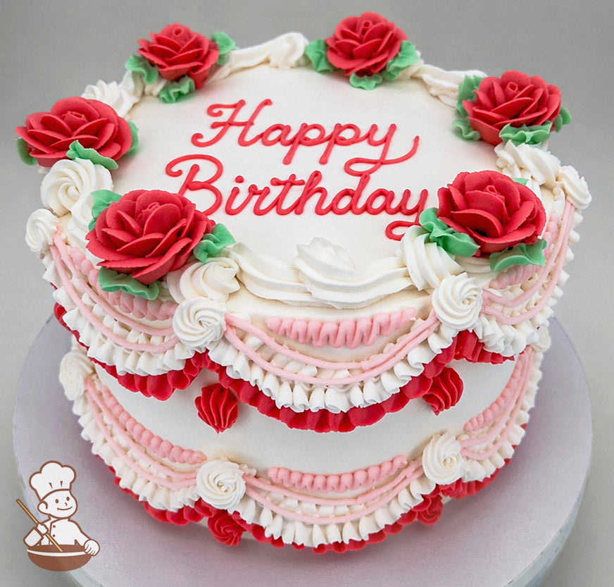 A single-tier white cake with red "Happy Birthday" text on top, decorated with red buttercream roses, green leaves, and pink and white piped swags.