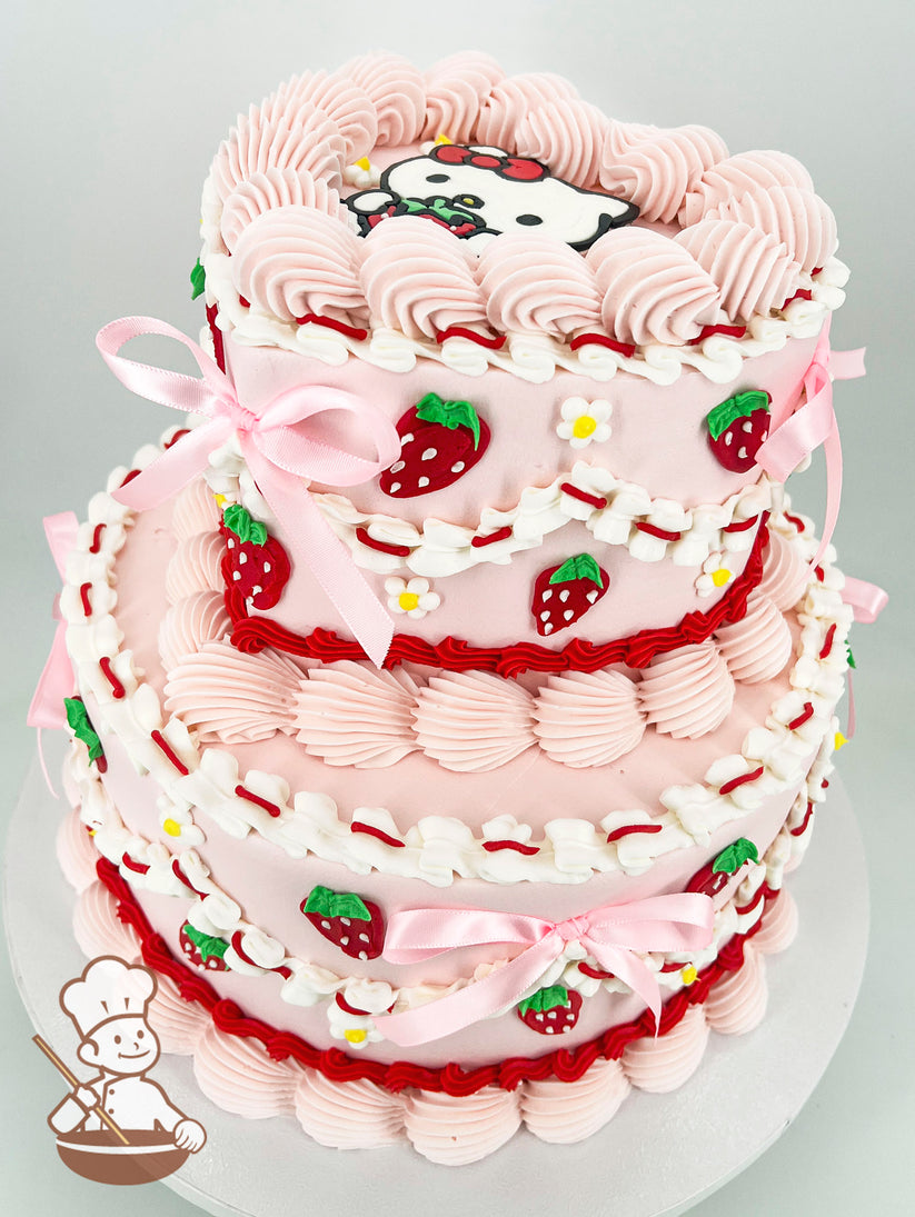 A two-tier pink cake decorated with piped strawberries, small flowers, pink ribbons, and a cartoon character on the top tier.