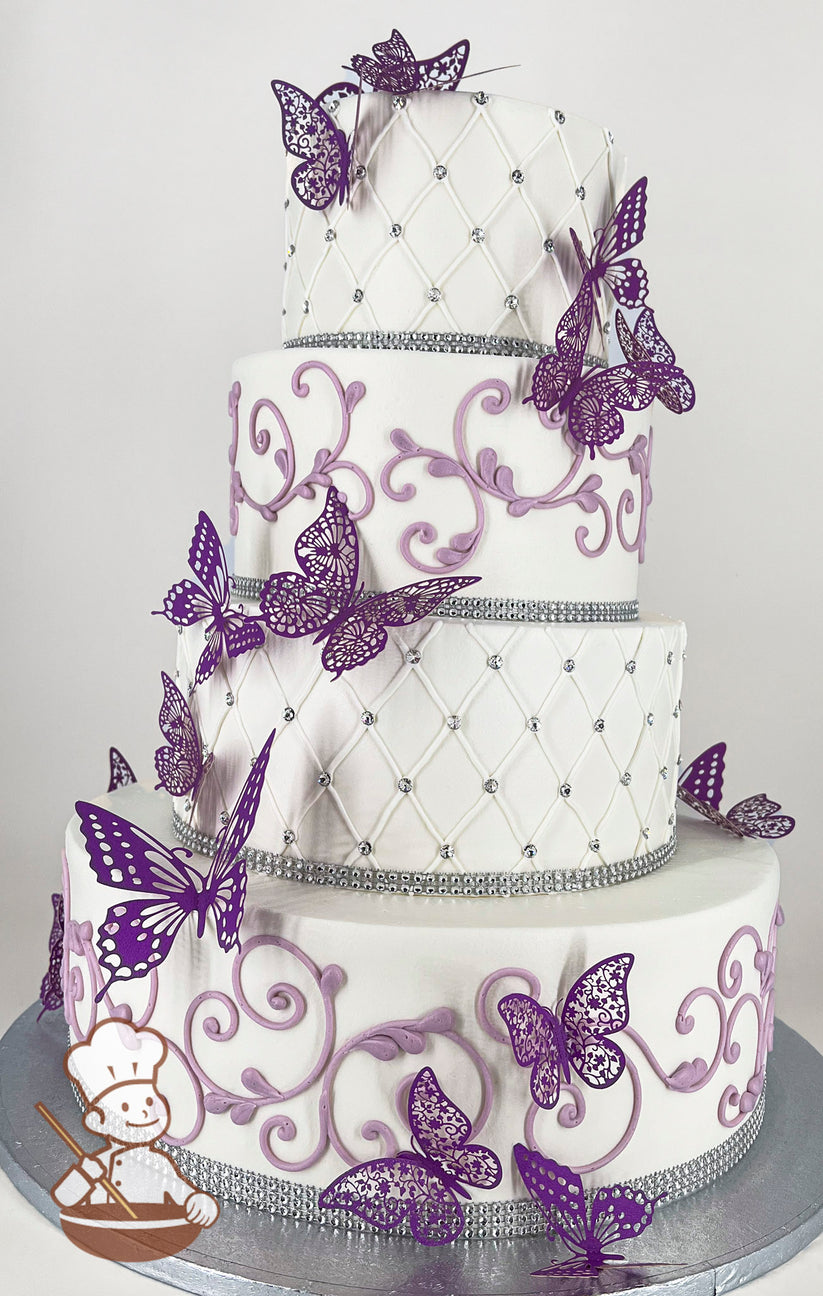 Four-tier white cake with purple butterfly decorations and lavender scrollwork. Each tier is adorned with silver rhinestone bands and quilted patterns.