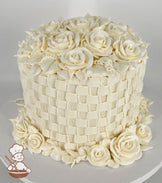 A single-tier cake with intricate white buttercream basketweave piping, topped and surrounded by detailed buttercream roses and leaves.