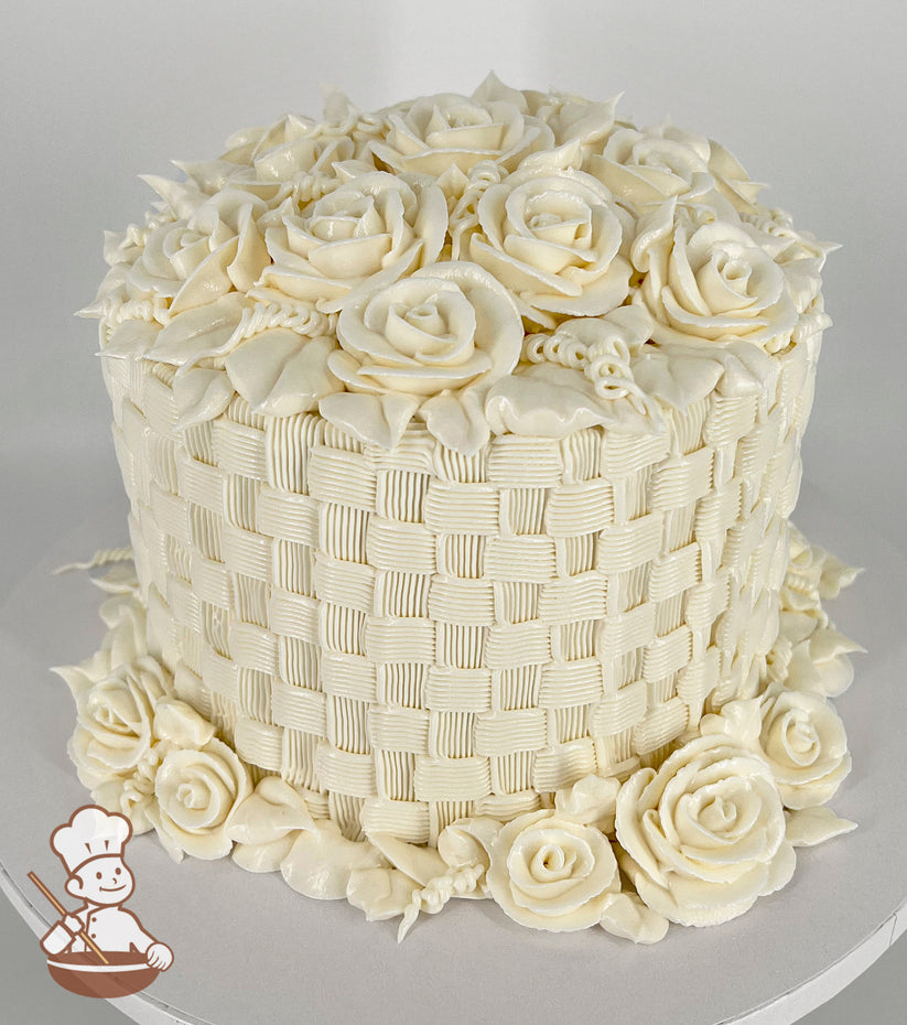 A single-tier cake with intricate white buttercream basketweave piping, topped and surrounded by detailed buttercream roses and leaves.