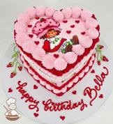 Heart-shaped birthday cake with pink and red frosting, featuring a cartoon character on top. Decorated with small hearts and "Happy Birthday Bella" written on the base.