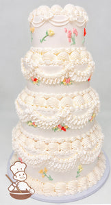 Four-tier white cake with intricate piped frosting swirls and scalloped designs. Decorated with small pastel-colored floral accents on each tier.