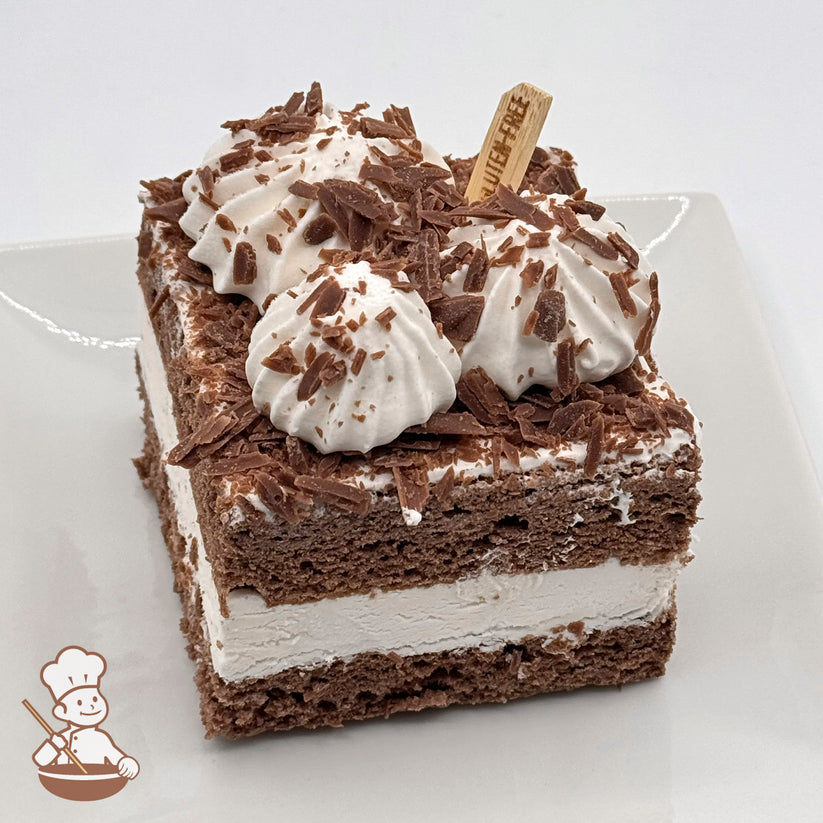 A slice of gluten-free chocolate chiffon cake topped with whipped cream and chocolate shavings on a white plate.