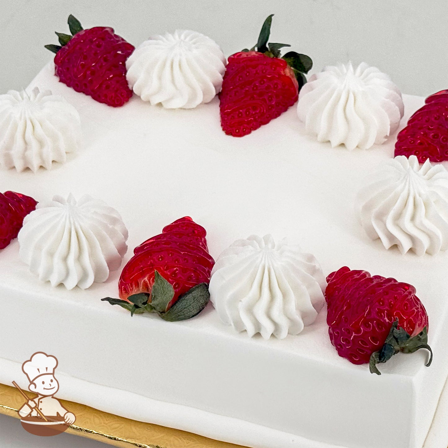 White sheet cake topped with strawberries and white buttercream swirls.