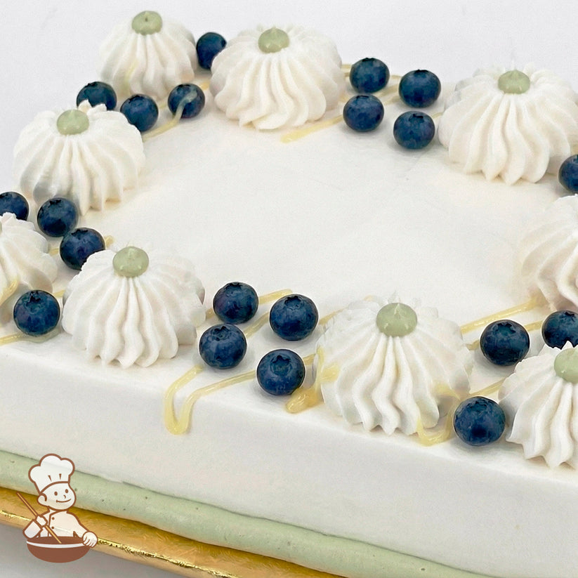White sheet cake with white whipped cream swirls, blueberries, white chocolate ganache drizzle, and a green buttercream border.