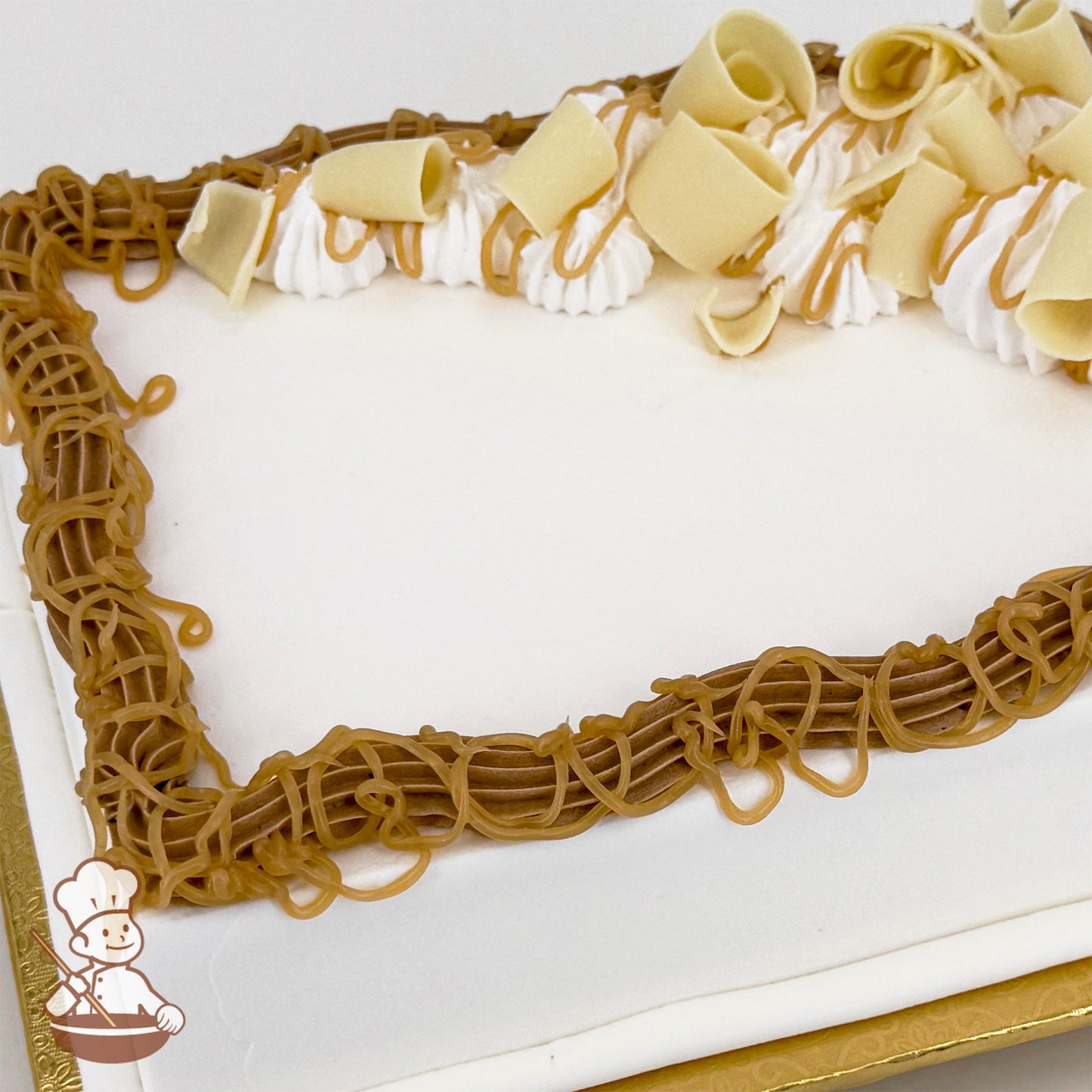 White sheet cake with caramel drizzle, white chocolate curls, and brown buttercream trim.