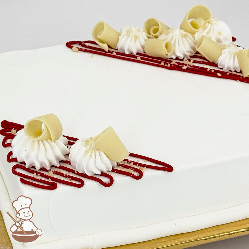 White sheet cake decorated with red buttercream lines, white chocolate curls, and dollops of piped white buttercream.