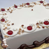 White sheet cake decorated with buttercream scrolls, raspberry preserve dots, diced almonds, and a piped brown base.