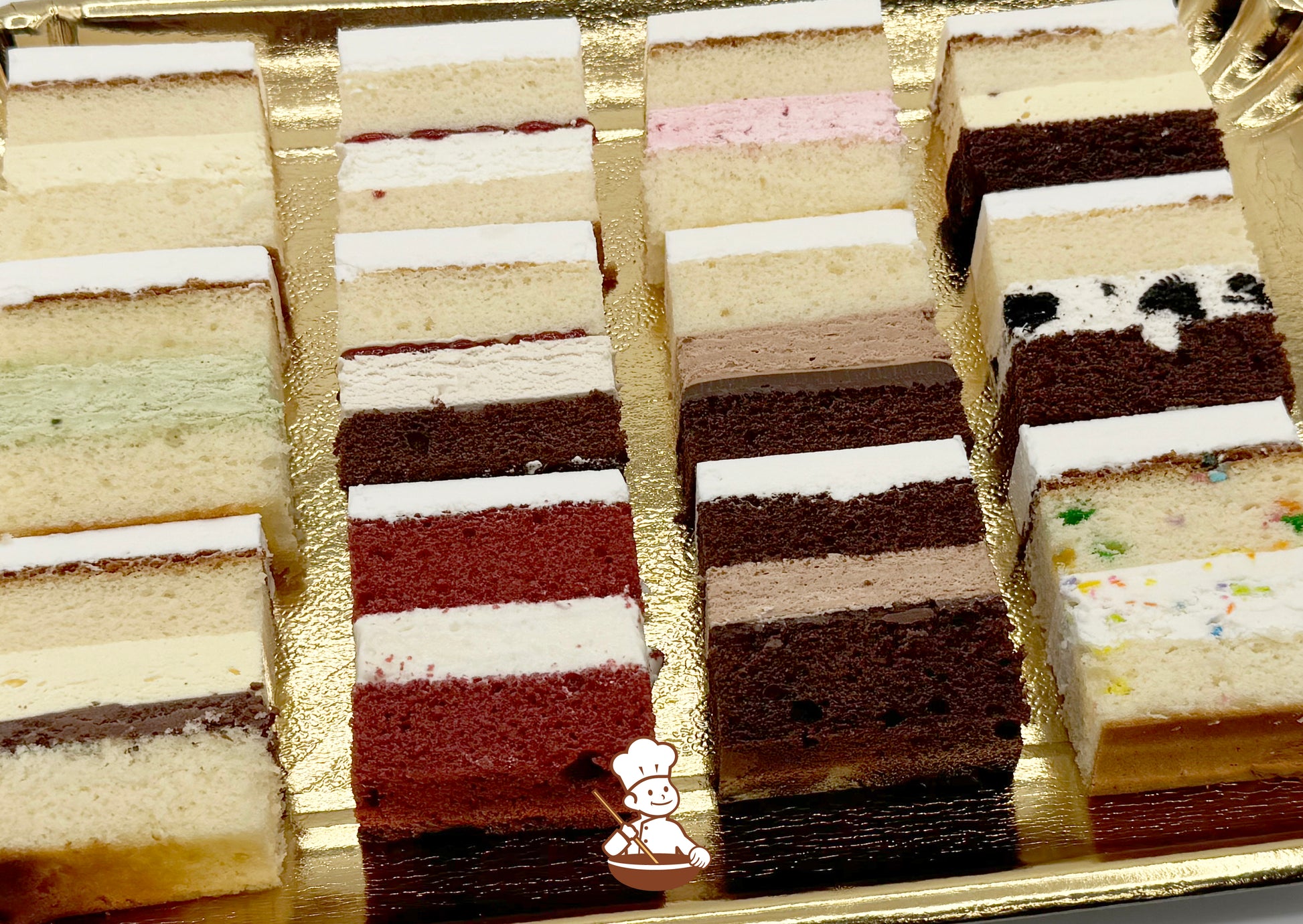 12 Cake Sample Slices arranged in a 4 by 4 grid on a gold colored tray. Slices are various flavors & are numbered 1 through 12. 1 is in the top left corner & 12 is bottom right.