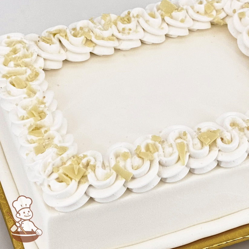 White sheet cake with squiggly buttercream trim, topped with crumbled white chocolate curls.