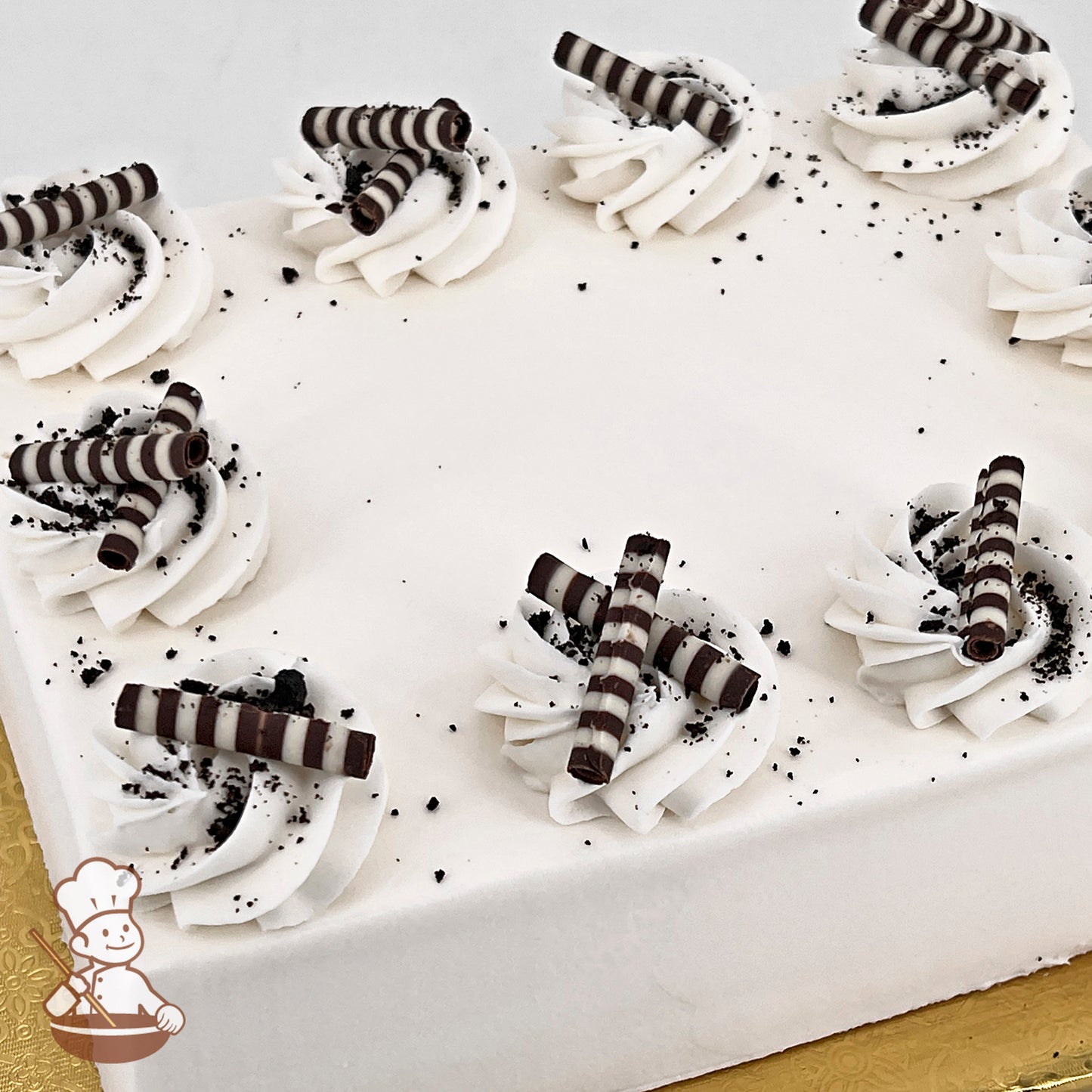 White sheet cake with buttercream swirls, chocolate sticks and chocolate crumbs.