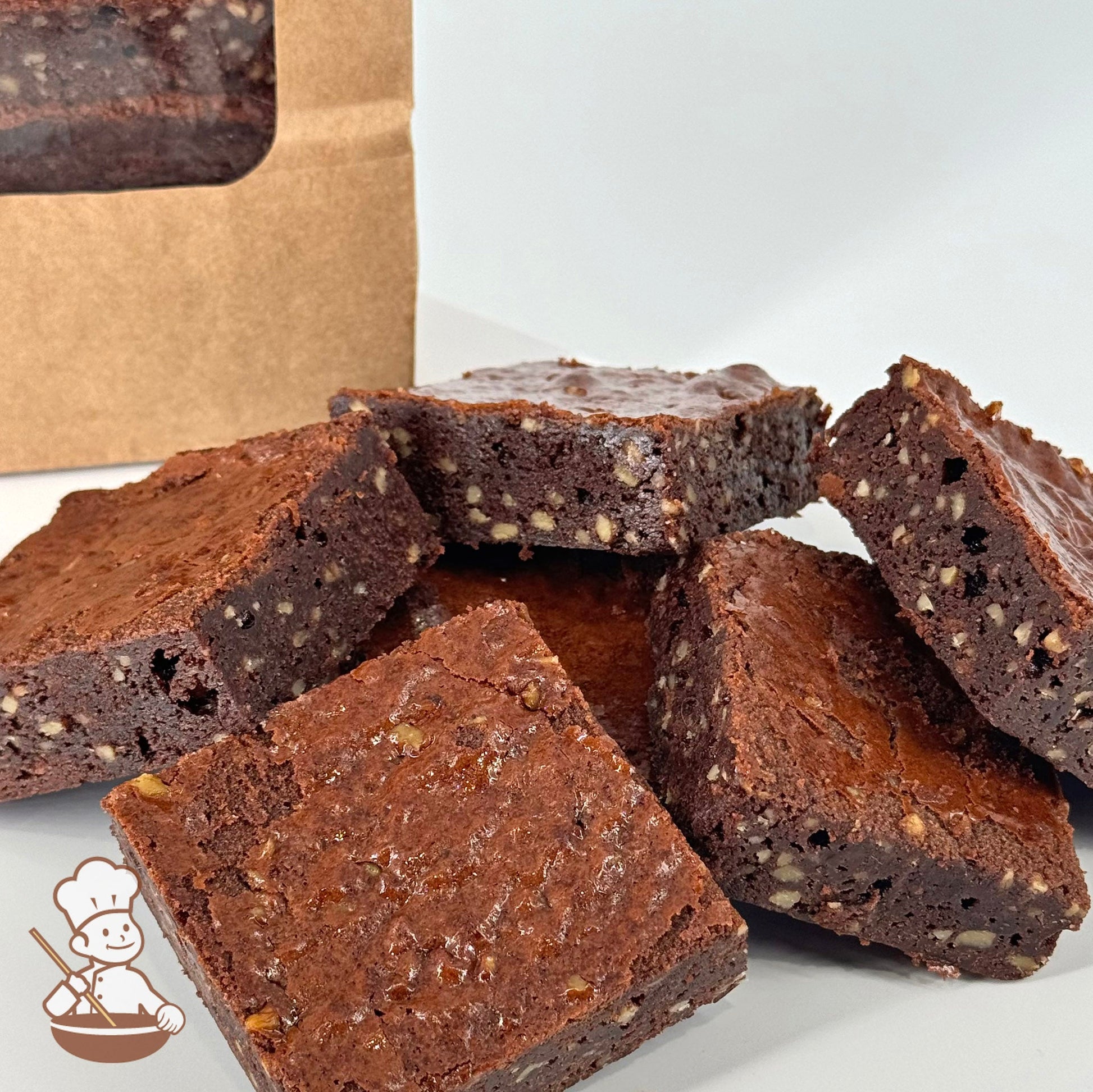 Six chocolate brownies made with Belgian chocolate and walnuts are arranged in front of a kraft window bag.