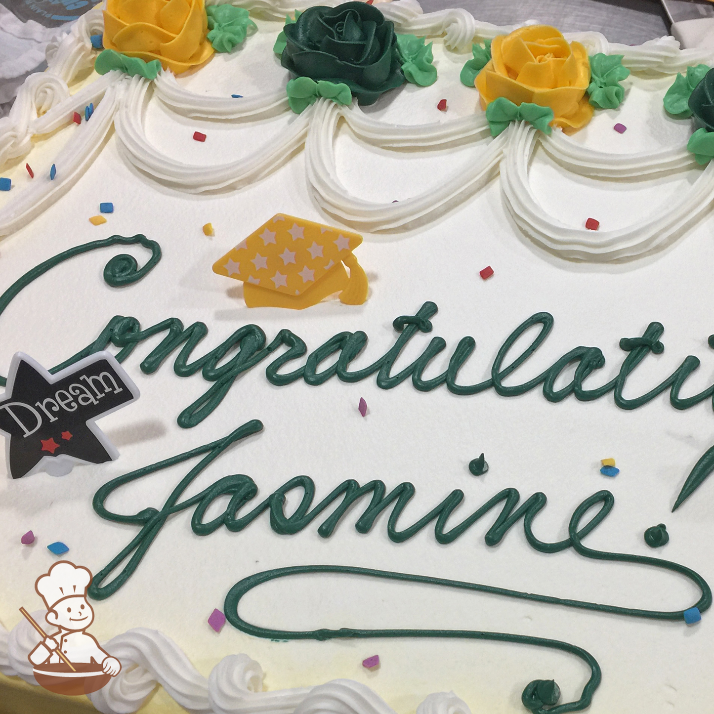 Graduation sheet cake with buttercream roses and piping with sprinkles and fun toy rings including grad's cap and "Dream".