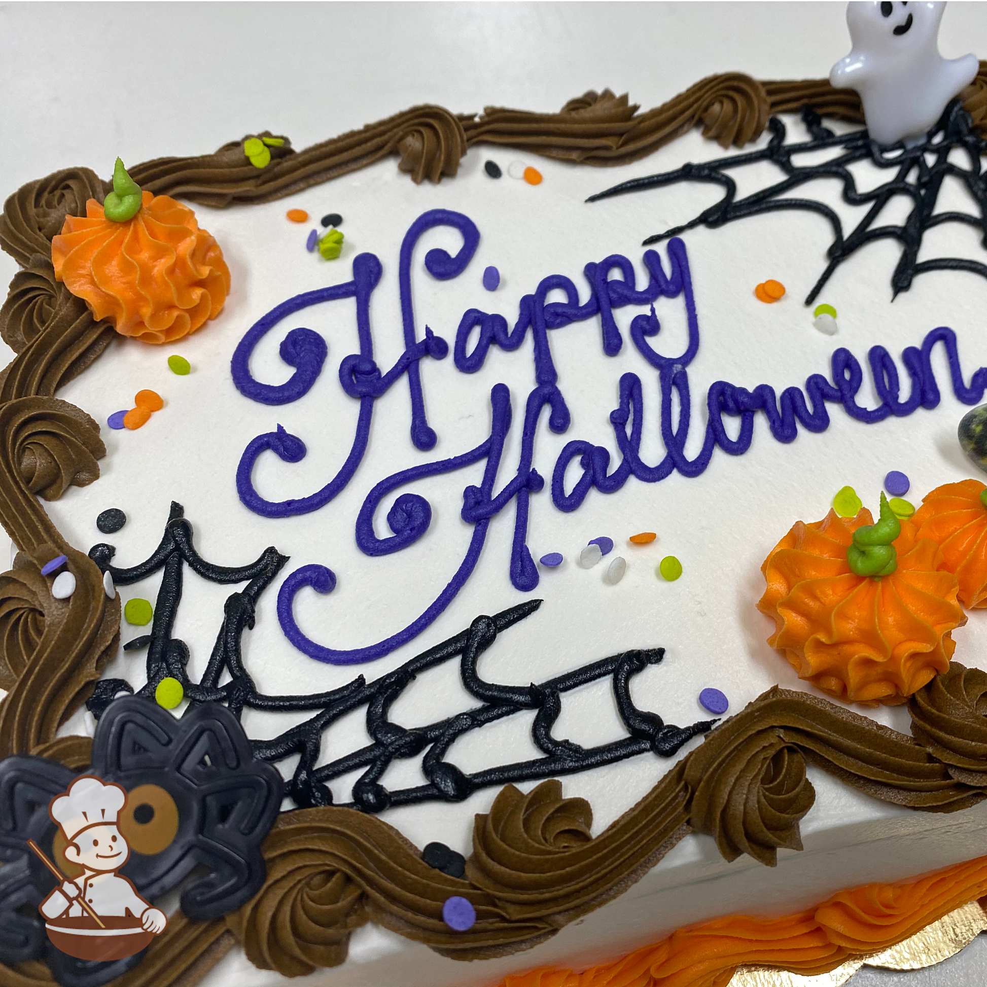 Halloween sheet cake with buttercream pumpkins, spider webs and sprinkles with ghost and spider toy rings.