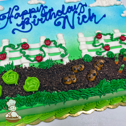 Birthday sheet cake with white fence behind vegetable garden filled tomatoes, lettuce, carrots and potatoes.