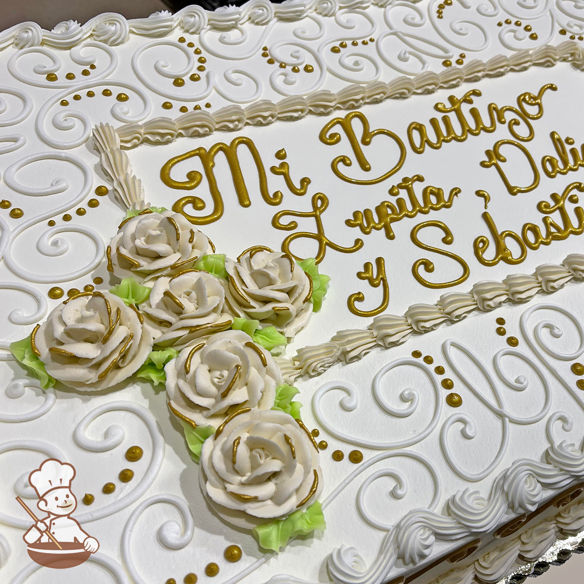 Baptism sheet cake with roses in a shape of a cross and scrolls with writing in gold piping inside a trimmed frame.