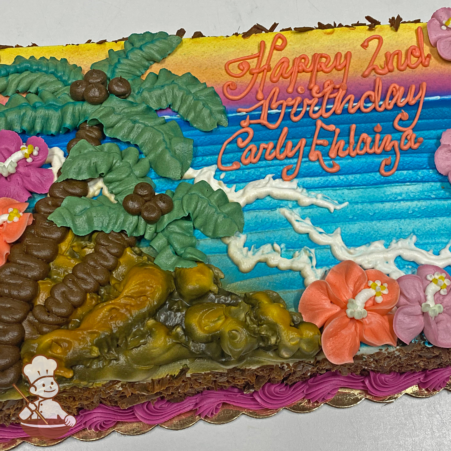 Birthday sheet cake with buttercream palm tree, ocean waves, hibiscus, and coconuts on cliff.