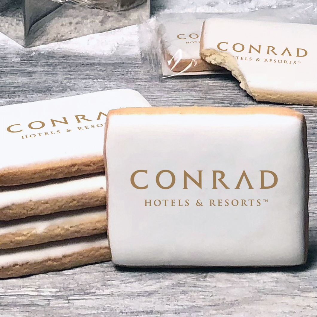 A stack of rectangle butter shortbread cookies with Conrad Hotels and Resorts logo printed directly on a white, lemon sugar icing.