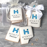 A stack of rectangular butter shortbread cookies with Hyatt House logo printed directly on a white, light sugar icing. Some cookies are shown in clear packaging with a twist-tie ribbon bow or inside an organza bag.