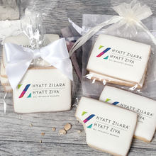 Load image into Gallery viewer, A stack of rectangular butter shortbread cookies with Hyatt Zilara logo printed directly on a white, light sugar icing. Some cookies are shown in clear packaging with a twist-tie ribbon bow or inside an organza bag.