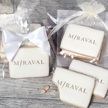 Load image into Gallery viewer, A stack of rectangular butter shortbread cookies with MiRaval logo printed directly on a white, light sugar icing. Some cookies are shown in clear packaging with a twist-tie ribbon bow or inside an organza bag.