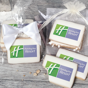 A stack of rectangular butter shortbread cookies with Holiday Inn Resort logo printed directly on a white, light sugar icing. Some cookies are shown in clear packaging with a twist-tie ribbon bow or inside an organza bag.