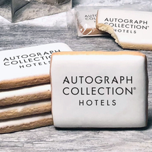 Load image into Gallery viewer, A stack of rectangle butter shortbread cookies with Autograph Collection logo printed directly on a white, lemon sugar icing.