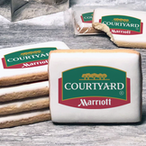 A stack of rectangle butter shortbread cookies with Courtyard logo printed directly on a white, lemon sugar icing.