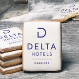 A stack of rectangle butter shortbread cookies with Delta Hotels logo printed directly on a white, lemon sugar icing.