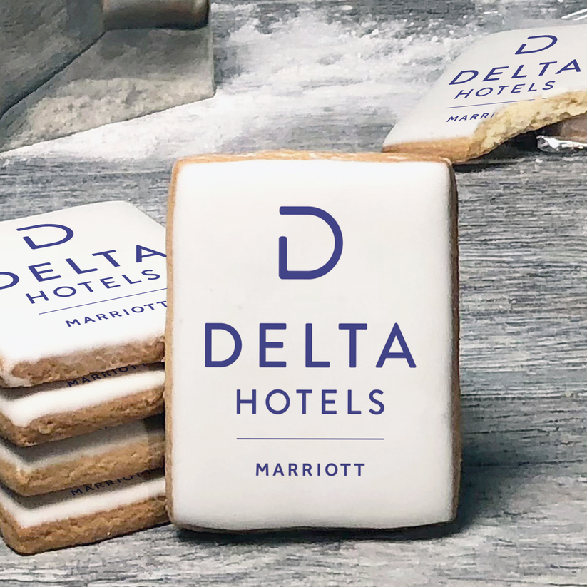 A stack of rectangle butter shortbread cookies with Delta Hotels logo printed directly on a white, lemon sugar icing.