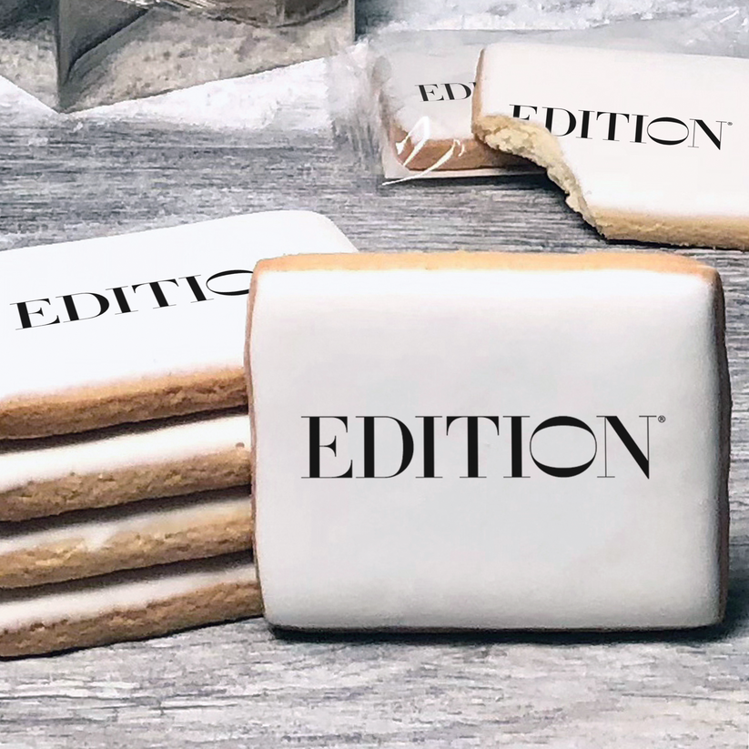 A stack of rectangle butter shortbread cookies with Edition logo printed directly on a white, lemon sugar icing.