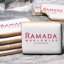 Load image into Gallery viewer, A stack of rectangle butter shortbread cookies with Ramada Worldwide logo printed directly on a white, lemon sugar icing.