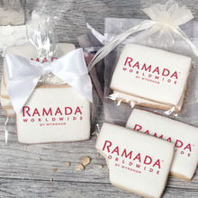 Load image into Gallery viewer, A stack of rectangular butter shortbread cookies with Ramada Worldwide logo printed directly on a white, light sugar icing. Some cookies are shown in clear packaging with a twist-tie ribbon bow or inside an organza bag.