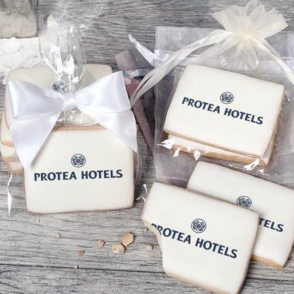 A stack of rectangular butter shortbread cookies with Protea Hotels logo printed directly on a white, light sugar icing. Some cookies are shown in clear packaging with a twist-tie ribbon bow or inside an organza bag.