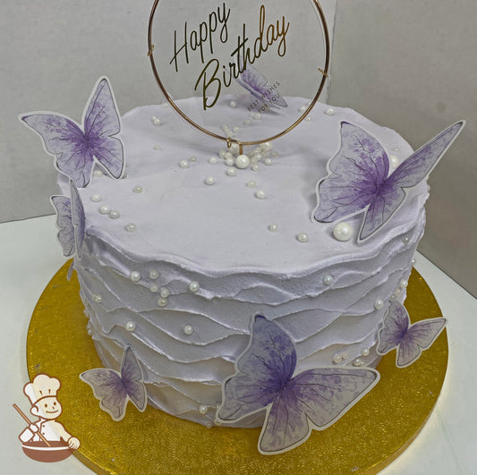 Single tier cake with lavender buttercream icing decorated with a wavy buttercream texture and plastic purple butterflies and white pearls.
