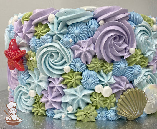 Single tier cake with buttercream rosette swirls and start tips in lavender, sage-green and different shades of blue for an under the sea theme.
